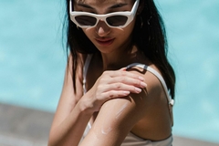 Image A woman putting sunscreen on her arm.