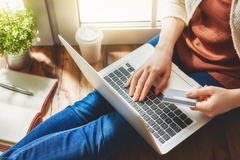 A woman at her laptop holding a credit card.