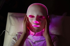 Woman wearing pink LED mask on face
