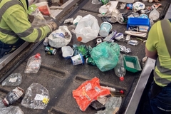 Image Workers sorting packaging waste on conveyor belt.