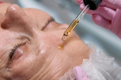 Image An older woman getting a serum applied to her face.