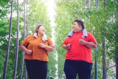 Obese man and woman jog in forest