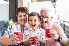Image grandparents with grandson holding glasses of red juice