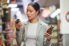 Image woman grocery shopping holds two products deciding which to buy