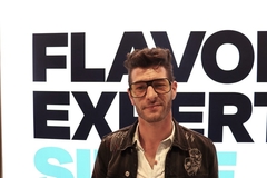a man in spectacles wearing a white shirt and black coat  at a trade show