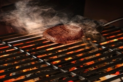Image Mosa Meat's cultivated burger being grilled on the barbecue.
