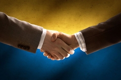 Image Hands shaking in front of the Ukrainian flag.