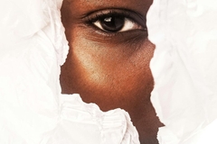 Person with dark skin looking through white paper