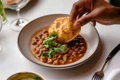 Image dipping bread in chickpea curry