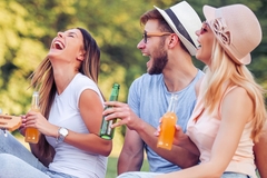 Image one young man and two women in the park with beer laughing