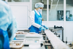 Image food factory worker in a blue apron and mask