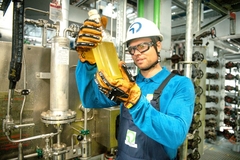 Image Worker at recycling plant holding bottle filled with pyrolysis oil.