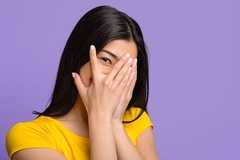 Image woman's eye peeking out of her hands covering her face