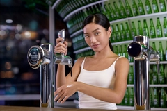 Image A woman pouring beer on her hand from the tap.