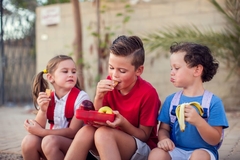 Image children sit outside and eat snacks