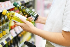 Image Shopper checking the label on edible oil bottles in the supermarket.