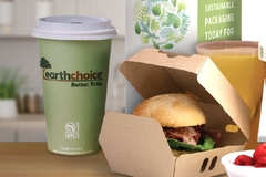 A burger in a box next to a cup