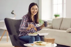Image A person sitting in a chair eating food