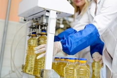 Image Girl worker at a factory on a conveyor background with bottles of vegetable oil