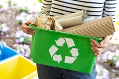 Image A person holding a green recycle bin.