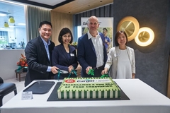 Image two women and two men cutting a big cake on a white table
