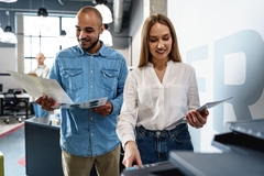 A person and person standing in a room with printed examples