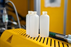 A group of plastic bottles on a yellow surface.