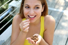 A sporty looking woman eating almonds out of the palm of her hand.