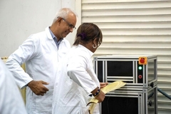 A person and person in lab coats standing in front of a machine