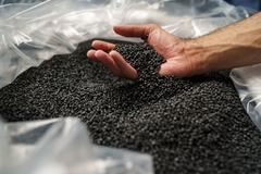 Image Black plastic resins in hand.
