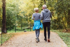 Image An older couple power walking in a park.
