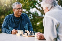 Image Two gentlemen playing chess outside in a park.