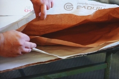 Image A person opening a brown paper bag.