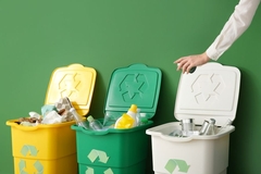 A person throwing garbage into recyclable container.