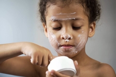 Image little girl applying skin care products to face