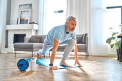 Image An older man exercising on a yoga mat in a brightly lit room.