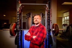 Image Man folds arms in front of weight lifting machine