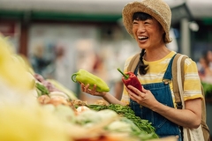 Image happy woman in market holds peppers