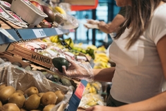 Image A shopper inspecting an avocado.