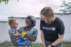 Image Unicef worker smiles at baby carried by mother