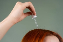 Image woman applying hair oil to scalp