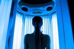 Image A woman standing in front of sun bed lights.