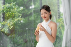 A woman smiles and gets ready to take a yellow supplement.
