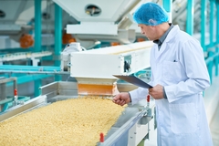 Image factory worker doing production quality inspection in food industry holding clipboard standing by conveyor belt