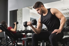 Man and woman in the gym lifting weights with their arms.