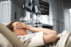 young woman with hand on face lying in hospital bed