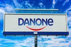 Image Danone sign against a bright blue sky with clouds.