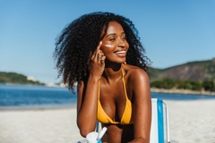 woman applying sunscreen to her face at the beach