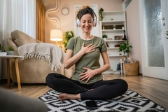 Image A woman doing yoga while listening to her headphones.