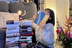 Image A woman holding a book next to books.